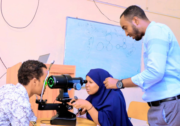Aden Adde International University Photo of instructor teaching optometry student how to examine a patient's eyes