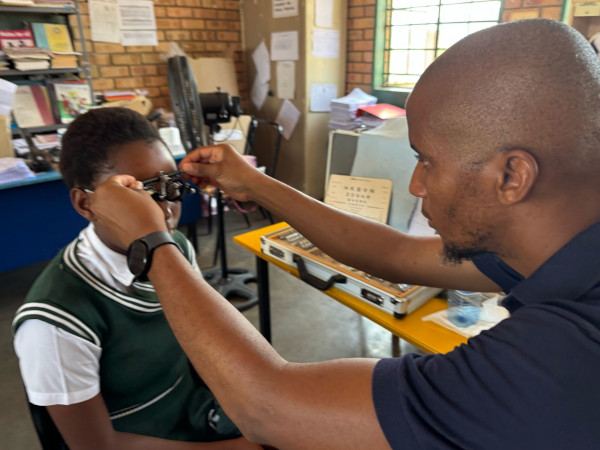 African Eye Institute Trust - Project photo Photo of an optometrist placing glasses on a child's face