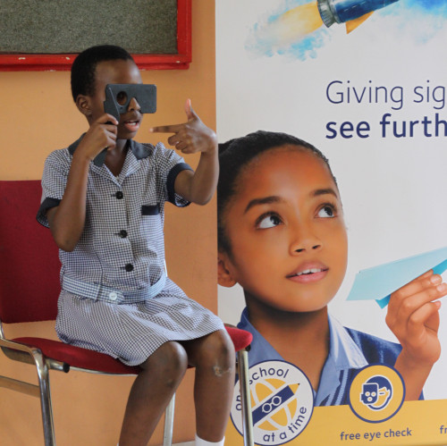 Berkeley Vision Image of young girls sitting on a chair holding an ocluder and looking at an eye chart as part of an eye exam.