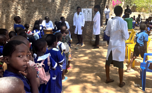 Canadian Vision Care - Guyana and Trinidad & Tobago Photo of optometry students giving eye exams to a group of children in an outdoor setting