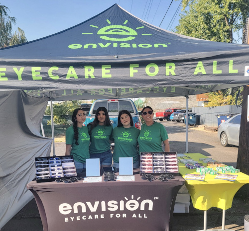 Envision Eyecare for All Photo of a tent booth with the staff of Envision EyeCare for All at a vision event.