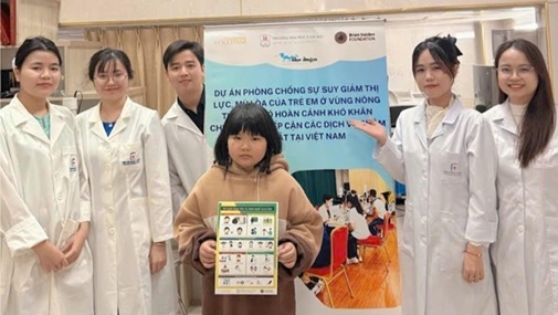A photo of five optometry students and a small child holding a chart, in front of a stand-up banner.