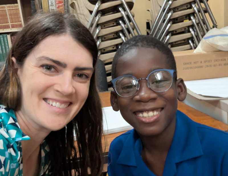 A Jamaican student named Othniel is pictured in a photo wearing his new glasses, and is next to an optometrist who helped him.